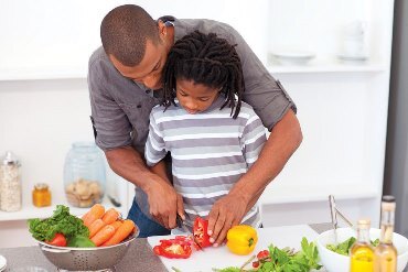 Child cooking healthy meal with father