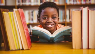 African American child reading a book in the library