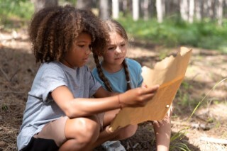 Two children using a map for a treasure hunt in a forest